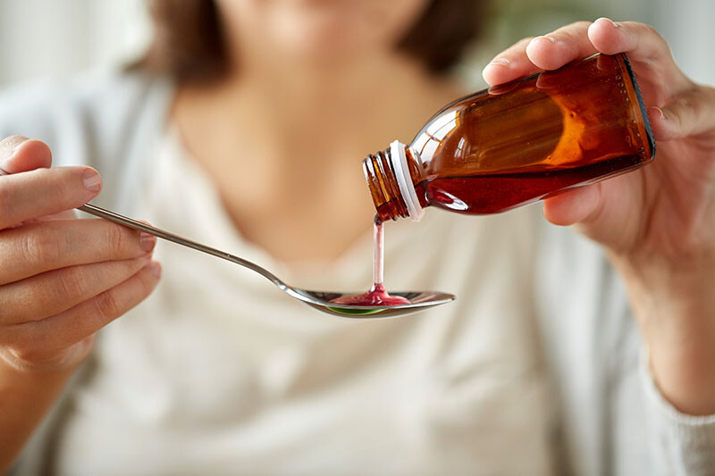 žena sipa sirup u kašiku